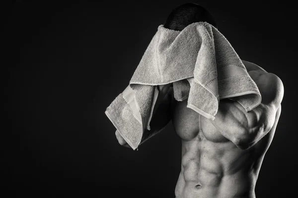 Muscular man with a towel in his hands on a dark background — Stock Photo, Image