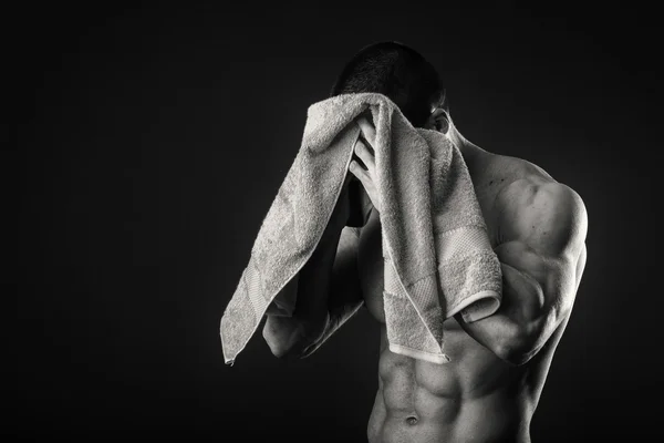 Kaslı adam ellerini karanlık bir arka plan üzerine bir havlu ile — Stok fotoğraf