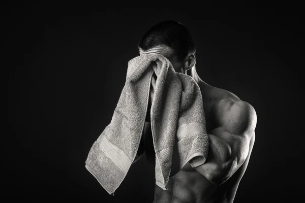 Kaslı adam ellerini karanlık bir arka plan üzerine bir havlu ile — Stok fotoğraf