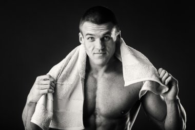 Kaslı adam ellerini karanlık bir arka plan üzerine bir havlu ile