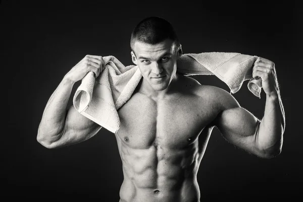 Muskularny mężczyzna z ręcznikiem w jego ręce na ciemnym tle — Zdjęcie stockowe