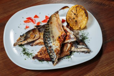 Beyaz bir plaka üzerinde ızgara sebzeli uskumru füme.