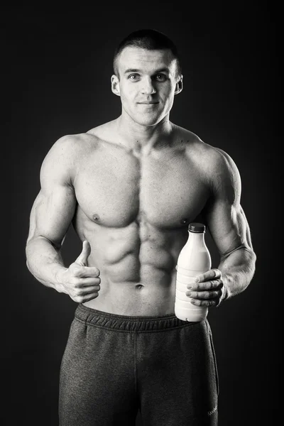 Uomo bodybuilder posa su sfondo grigio L'uomo sta tenendo uno shaker per le bevande. Uomo che beve un frullato proteico, acqua, aminoacidi dallo shaker. Sport, nutrizione sportiva, additivo alimentare . — Foto Stock