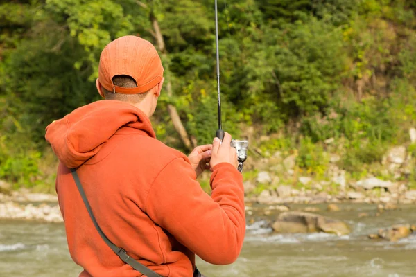 紡績から山川の若い漁師。渓流での釣り。キャッチのプロセスと漁師の貿易に焦点を当てください。釣りと自然の雑誌、ポスター、ウェブサイトの写真. — ストック写真