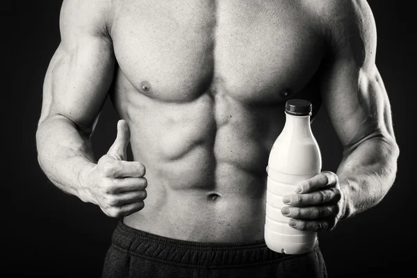 Muž kulturista pózuje na šedém pozadí člověk drží šejkr pro nápoje. Člověk pije proteinový koktejl, voda, aminokyseliny ze šejkru. Sport, sportovní výživa, potravinové aditivum. — Stock fotografie
