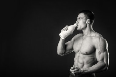 Adam gri arka plan üzerinde poz adam vücut geliştirmeci bir shaker içecekler için tutuyor. Adam bir protein shake, su, amino asitler shaker içme. Spor, spor ve beslenme, Gıda katkı maddesi.