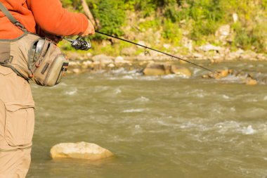 Genç balıkçı iplik bir dağ nehir üzerinde. Dağ nehirler balıkçılık. Yakalama işlemi ve ticaret balıkçı odaklanarak. Balıkçılık ve doğal dergiler, posterler, Web siteleri için fotoğraf.