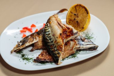 Beyaz bir plaka üzerinde ızgara sebzeli uskumru füme.