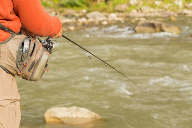 Genç balıkçı iplik bir dağ nehir üzerinde. Dağ nehirler balıkçılık. Yakalama işlemi ve ticaret balıkçı odaklanarak. Balıkçılık ve doğal dergiler, posterler, Web siteleri için fotoğraf.