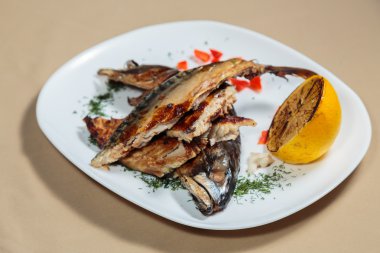 Beyaz bir plaka üzerinde ızgara sebzeli uskumru füme.