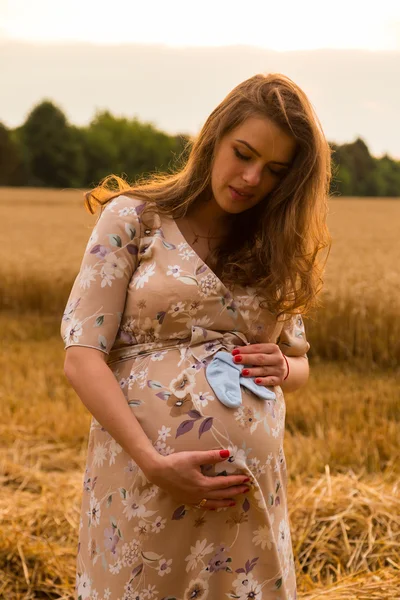 Těhotná žena v pšeničné pole. Šťastná žena v poli. Žena se raduje nenarozeného dítěte. Upřímné emoce a radostný pocit. Krajina nádherná země. Pšeničné pole čeká sklizeň. — Stock fotografie