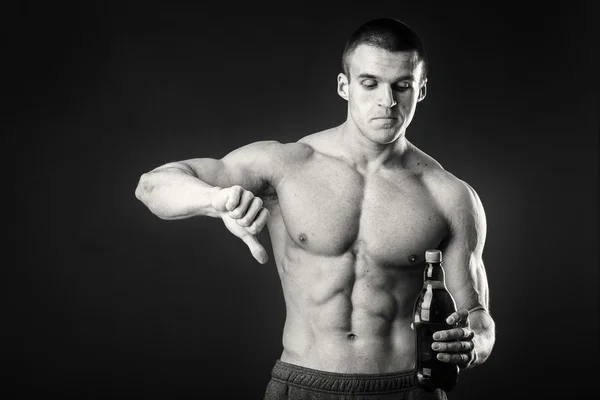 Fisiculturista masculino mostra que a cerveja é ruim . — Fotografia de Stock