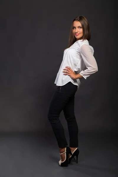 Jovem empresária elegantemente vestida. A imagem de uma bela jovem empresária. Menina de calças pretas e uma camisa branca em um fundo escuro. Foto para revistas de moda e sociais, sites . — Fotografia de Stock
