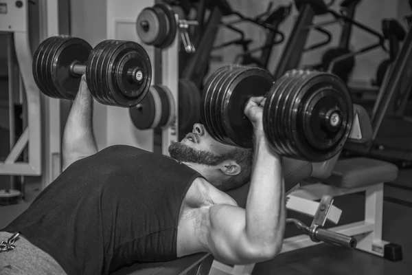 Man op de sportschool. Man maakt oefeningen met barbell. Sport, voeding, halters, spanning, oefening - het concept van een gezonde levensstijl. Artikel over fitness en sport. — Stockfoto