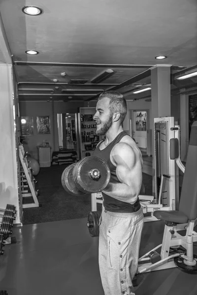 Man at the gym. Man makes exercises with barbell. Sport, power, dumbbells, tension, exercise - the concept of a healthy lifestyle. Article about fitness and sports. — Stock Photo, Image