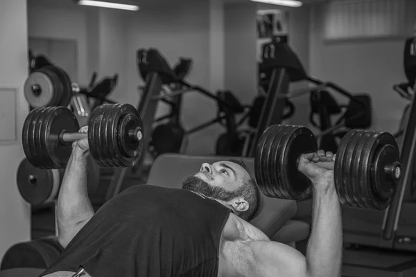 Hombre en el gimnasio. El hombre hace ejercicios con barra. El deporte, el poder, las pesas, la tensión, el ejercicio - el concepto de un estilo de vida saludable. Artículo sobre fitness y deportes . — Foto de Stock