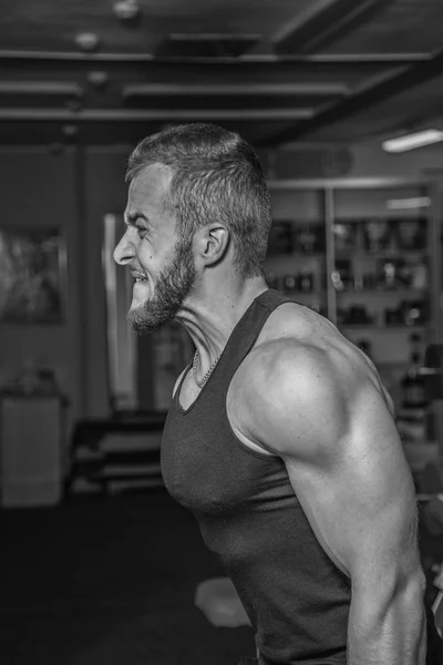 Um homem no ginásio. O homem faz exercícios com a campainha. Esporte, poder, halteres, tensão, exercício - o conceito de um estilo de vida são. Artigo sobre fitness e esportes . — Fotografia de Stock