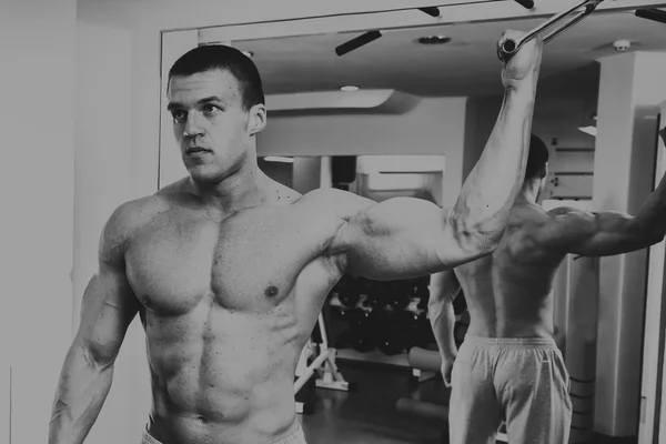 Forte uomo muscolare che fa esercizi in palestra . — Foto Stock