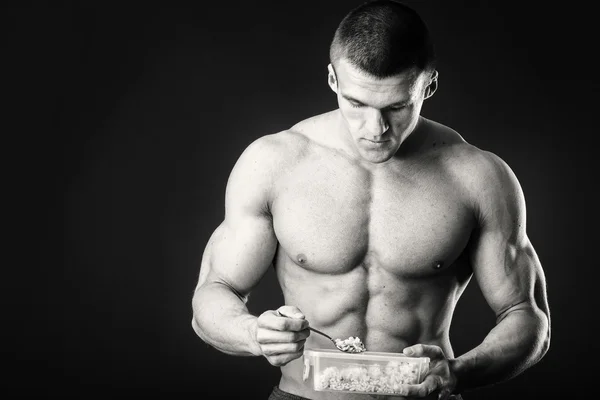 근육 남자는 어두운 배경에 코 티 지 치즈를 먹는. — 스톡 사진