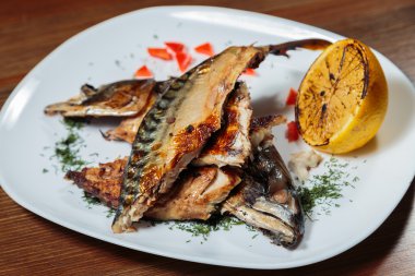 Beyaz bir plaka üzerinde ızgara sebzeli uskumru füme.