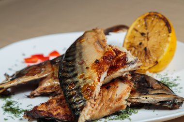 Beyaz bir plaka üzerinde ızgara sebzeli uskumru füme.