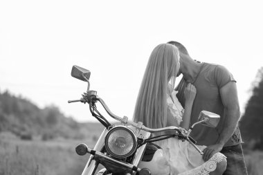 Siyah ve beyaz fotoğraf motorcu çift bir motosiklet alanında.