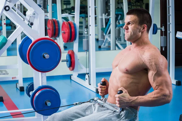 Forte uomo muscolare che fa esercizi in palestra . — Foto Stock