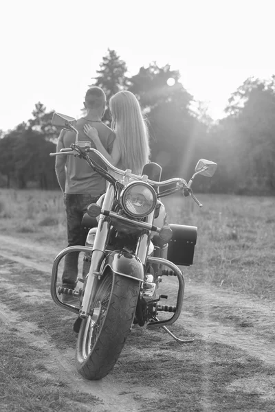 Preto e branco foto motociclista casal em uma motocicleta no campo . — Fotografia de Stock