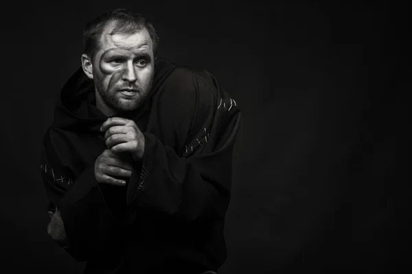 Hermoso y fascinante actor de teatro de juego en cámara. Foto en blanco y negro del actor disfrazado de mendigo sobre un fondo oscuro. Imagen escénica bellamente decorada y maquillaje profesional . — Foto de Stock