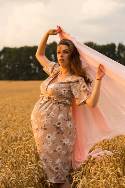 Těhotná žena s kapesníkem v ruce v pšeničné pole. Šťastná žena v poli. Žena se těší nenarozeného dítěte. Upřímné emoce a radostný pocit. Nádherná krajina. Pšeničné pole čeká sklizeň. — Stock fotografie
