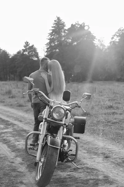 Preto e branco foto motociclista casal em uma motocicleta no campo . — Fotografia de Stock