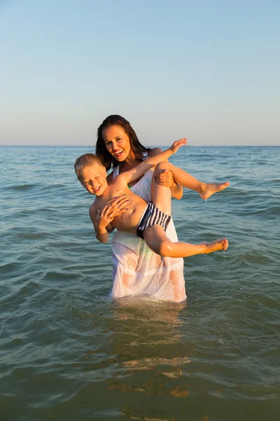 Young mother with son playing in the sea. A beautiful young mother and little boy happy gaming in water. Family holidays at sea. Photo for family and social magazines, posters and websites. Royalty Free Stock Photos