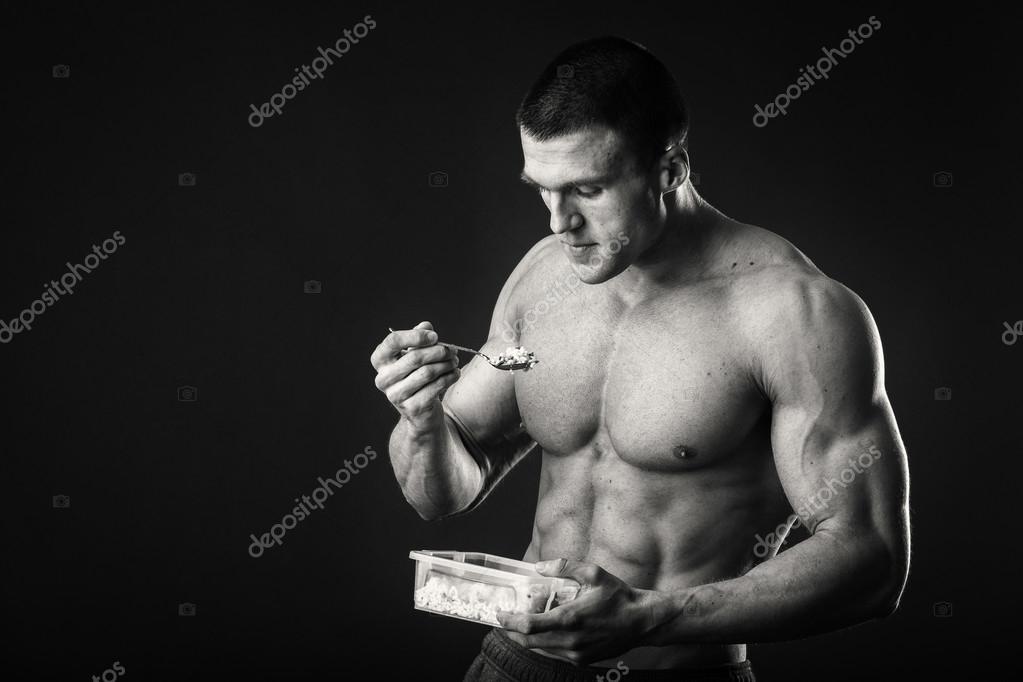 Muscular Man Eats Cottage Cheese On A Dark Background Stock