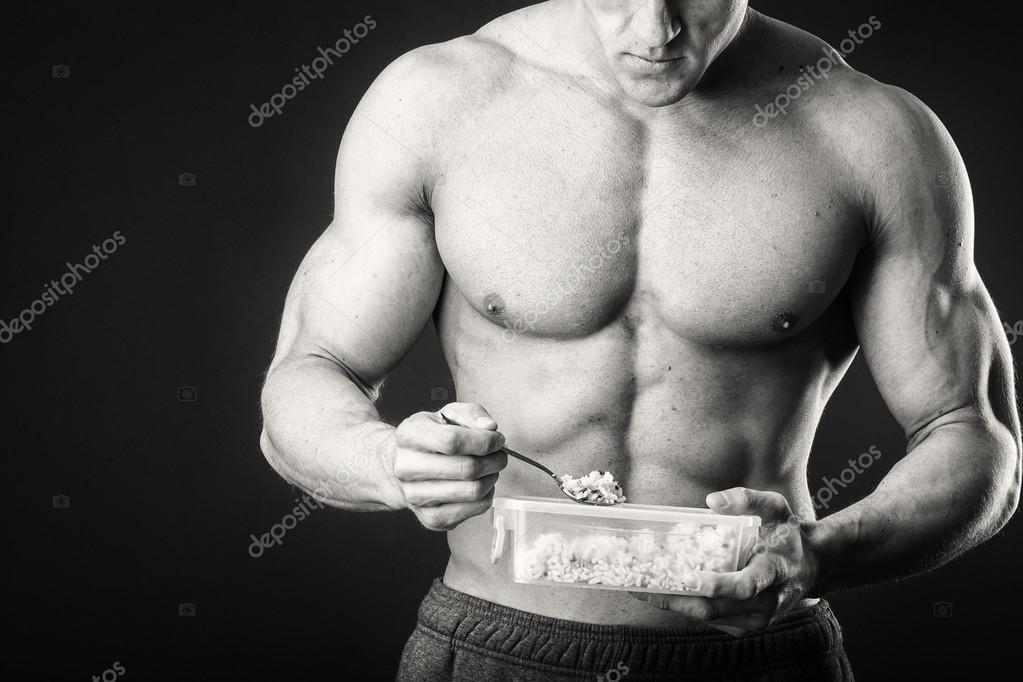 Muscular Man Eats Cottage Cheese On A Dark Background Stock