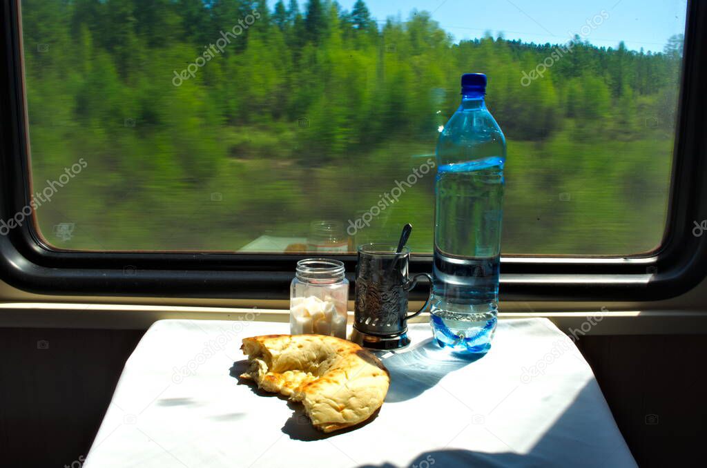 Train compartment table with glass and water moving forest background