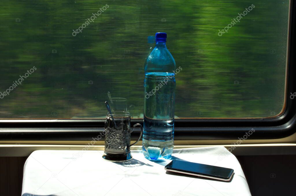 Train compartment table with glass and water moving forest background