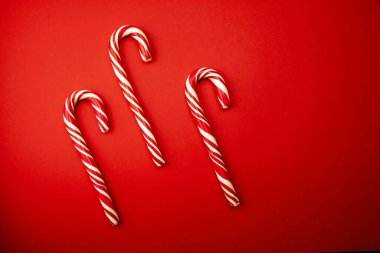 Kırmızı ve sarı arkaplanda bir dizi noel öncesi fotoğraf. Lolipoplar ve bayramın özellikleri, üst görünüm, düz tasarım.