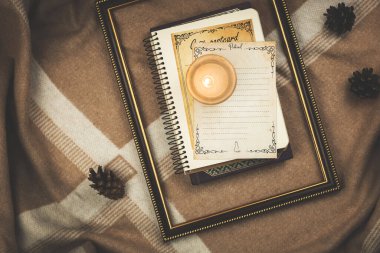 Ahşap çerçeveli rahat kompozisyon, kitaplar ve arka planda sıcak battaniyeler ve çam kozalakları, kış veya sonbahar temalı fotoğraf