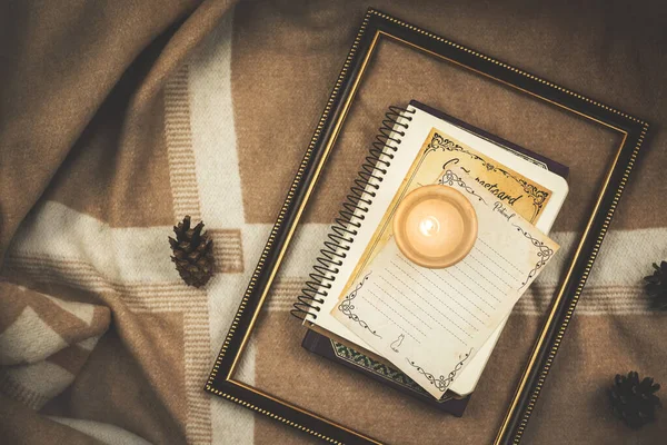 Ahşap çerçeveli rahat kompozisyon, arka planda kitaplar ve mum sıcak ekoseler ve koniler, kış sonbahar temalı fotokopi alanı