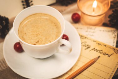 Bir fincan sıcak çikolata ve içinde dekorasyon ve mumlar olan samimi kartlar, yılın resmi.