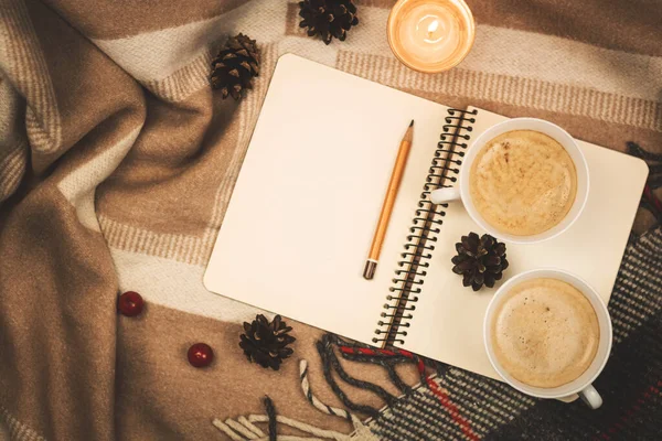 Kış konforu ve ruh hali, iki fincan sıcak kahve ve kapuçino, ekoseyle ilgili notlar için bir not defteri, fotokopi uzay fotoğrafı.