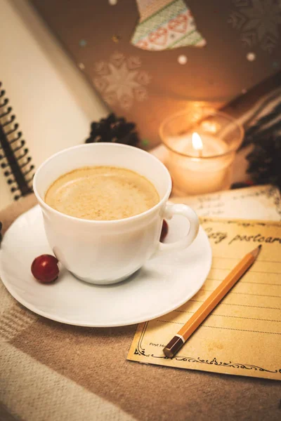 Bir fincan sıcak çikolata ve yılın kompozisyonu dekorasyon ve mumlarla dolu samimi kartlar.