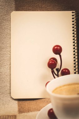 Boş not defteri sayfası, rahat bir ortam, bir fincan kahve ve dekorasyon.