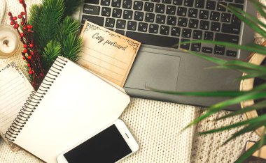 Sıcak kış işyeri ve çalışma alanı, kartpostal, not defteri ve dizüstü bilgisayar örülmüş kalın süveter, düz kompozisyon fotoğrafı