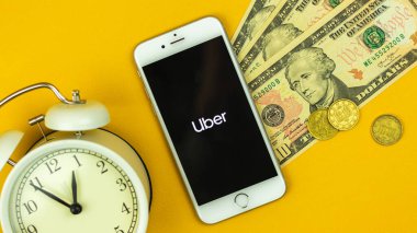 Kharkov, Ukrayna - 5 Şubat 2021: Uber hizmet uygulama logosu ve simgesi Apple akıllı telefon ekranında, nakit para ve para konsepti fotoğrafı ile yaratıcı düz zemin