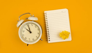 Kopya alanı not defteri ve alarm saati ile sarı arkaplan, zaman yönetimi konsepti, kendi kendini düzenleme kompozisyonu ve afiş fotoğrafı