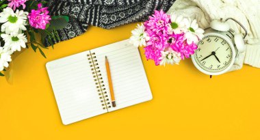 Kalemli boş not defteri, sarı arkaplanda bahar kompozisyonu çiçekli, bayanların bayram temalı fotoğrafı.