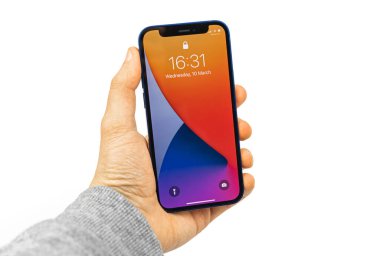 Kharkov, Ukrayna - 12 Mart 2021: Elde beyaz izole edilmiş arka planda kilitli ekranlı Apple iPhone 12