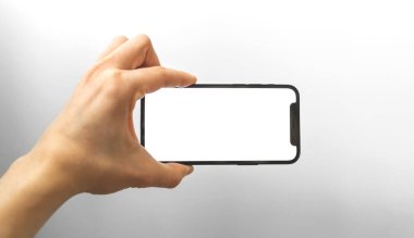 Kharkov, Ukrayna - 3 Nisan 2021: El, Apple iPhone 12 'yi yatay olarak tutuyor, boş beyaz ekran ile modelleme yapıyor