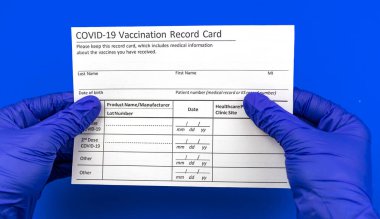 Coronavirus bağışıklık konsepti, aşı kayıt kartı doktorun elinde mavi arka planda.